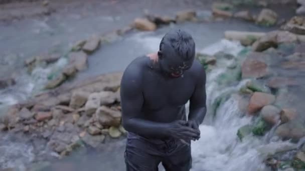 男泥の川で彼の顔により多くの泥を取得 ナチュラルスパのコンセプト — ストック動画