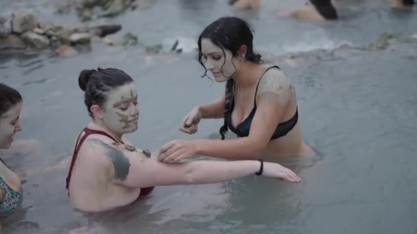 水の中に彼女の友人の腕の上に石を置く豪華な女の子 ナチュラルスパのコンセプト — ストック動画