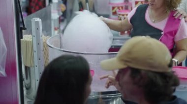 Bir kadın elleri bir çiftin bakışları altında pamuk şeker hazırlar - İspanyol Fuarı konsepti