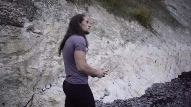 遠隔操作で海岸沿いを長い髪を歩く筋肉質の男 ヨーロッパ旅行ウェブサイト — ストック動画