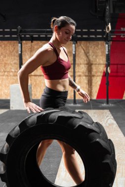 Kafkas kız atlet büyük bir spor salonunda büyük bir traktör tekerleği yuvarlıyor - Crossfit kavramı