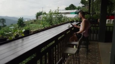 Kısa saçlı çocuk Kuzey Tayland 'da kahve içerken telefonla konuşuyor.