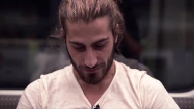 Sakallı yakışıklı adam yeraltı araba adasında otururken gülümsüyor.