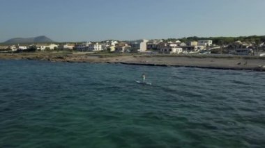 İspanyol adam deniz kıyısında sörf yapıyor. Ada turizmi yakınlarında.