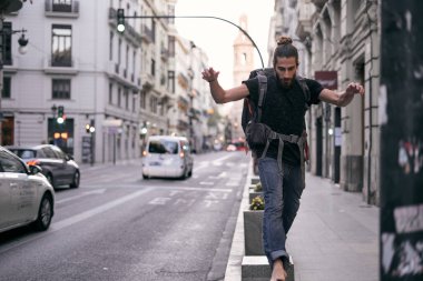 Beyaz saçlı, sakallı, sırtında sırt çantası olan, çıplak ayakla şehir caddesinde zıplayan, valencia, İspanya sırt çantalı seyahat konsepti olan bir adam.