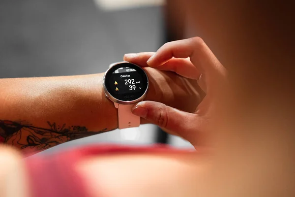 Spor yaptıktan sonra kalorilerinin yandığını gösteren zeki beyaz bir kadının sol koluna yakın çekim - Crossfit konsepti