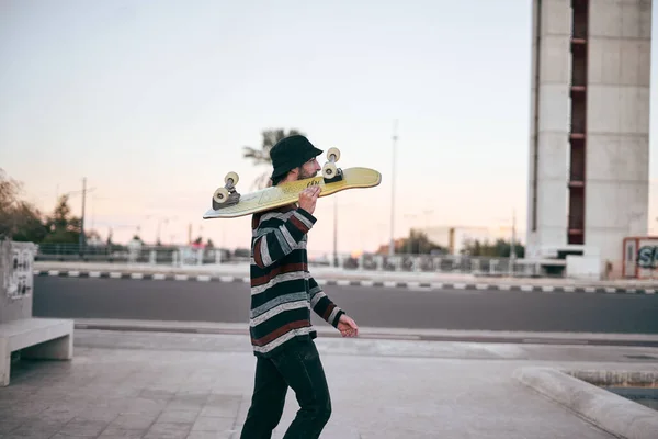 줄무늬 스웨터를 피어싱을 귀여운 비니를 두르고 스케이트보드를 스타일 도시의 코카서스 — 스톡 사진