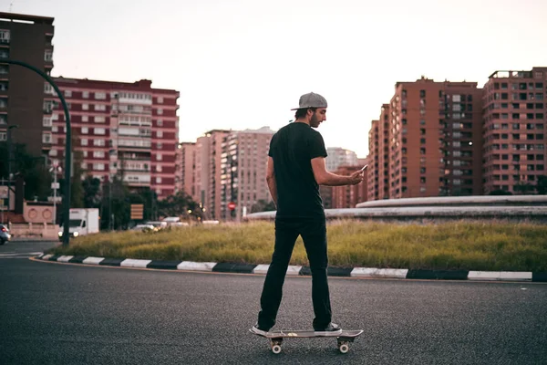 Kavkazský Mladý Muž Černém Tričku Čepici Hlavě Projíždí Skateboardem Dívá — Stock fotografie