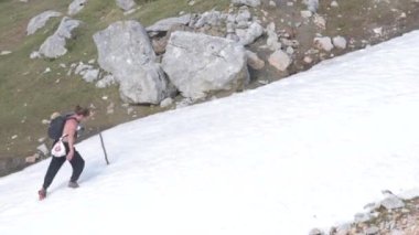 Uzun saçlı, sopalı yetişkin bir adam İspanya 'nın kuzeyinde, karlı bir dağda eğleniyor.