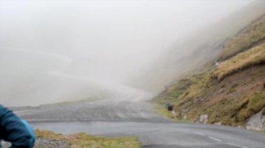 Dağlarda yürüyen mavi ceketli kapüşonlu bir adama yaklaş - seyahat konsepti