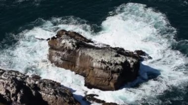 Denizin ortasındaki büyük kaya dalgalar tarafından vuruluyor.