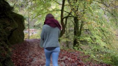 Ormanda yürürken sırtında sırt çantasıyla gezen bir kız.