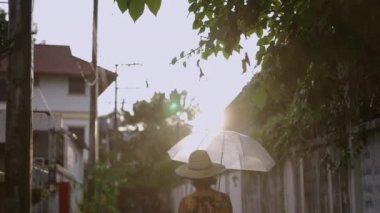 Güneş doğarken gezen bir kadın hala yağmur yağıyorken - şehir videosu