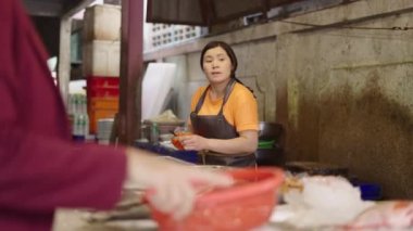 Taylandlı balıkçı müşteriyle konuşurken Tayland 'ın Bangkok kentindeki bir balık pazarında karides soyuyordu.