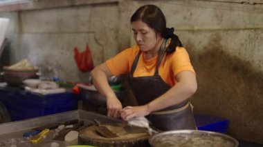 Tayland, Bangkok 'ta geleneksel bir balık pazarında koruma olmadan taze balık kesen Asyalı balıkçı - geleneksel Tayland işi