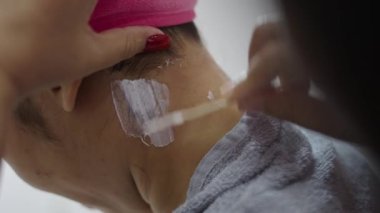 Applying hair removal wax paste with a stick on woman neck - Health concept