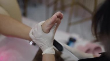 Close up shot of a pedicure expert woman filing a client left foot in a nail salon - Health concept
