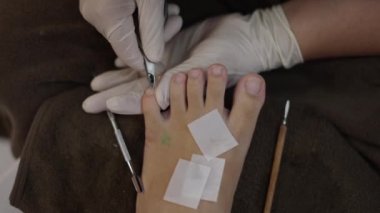 Close up of pedicure expert hands using a cuticle trimmer on left foot - Health concept