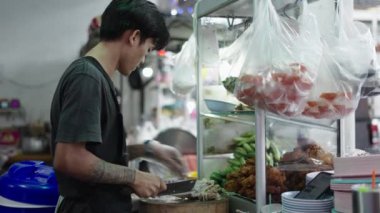 Young thai cook cleaning table and knife after cut a chicken - Traditional thai street food