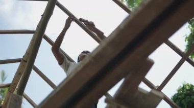 Low view of Young asian man using a hammer to create a roof - 4K Horizontal video