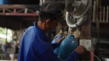 Adult thai man plugging a tool into a socket in a factory - 4K Horizontal video