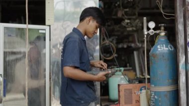 Young handsome real worker using an angle grinder and smiling to the camera - 4K Horizontal video