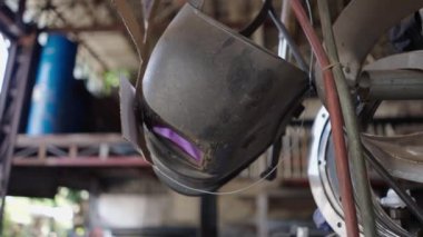 Endüstriyel metal fabrikasında asılı kirli kaynak miğferi - 4K Yatay video
