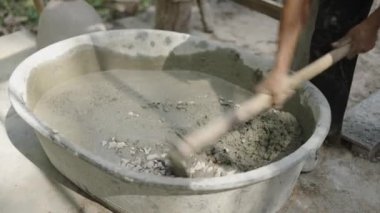 Unrecognizable man mixing concrete with rocks in a building site - 4K Horizontal video