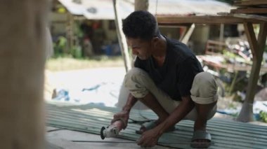 Adult asian man using a disk grinder while smoking with no protection - 4K Horizontal video