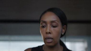 Close up of young black woman looking at the camera and running in a treadmill - Lifestyle concept