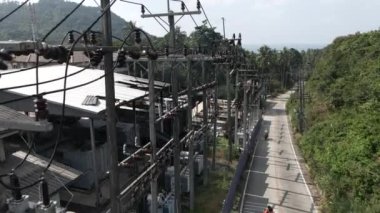 Motorbikes passing by a road close to a electricity power plant surrounded by mountains - Drone shot