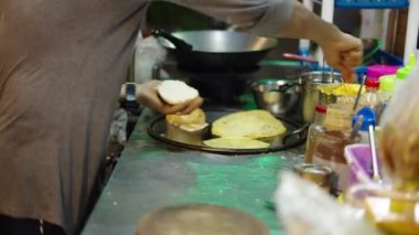 Tayland sokak satıcılarının geleneksel Tayland yemeği olan hamburger ekmeğine tereyağı sürerken yakın plan çekimleri.