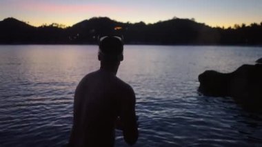 Genç adam Tayland 'da egzotik bir adada gün batımını sosyal medya için videoya çekiyor.