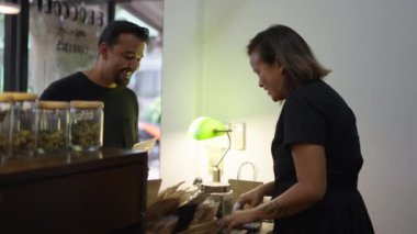 Asyalı perakendeci kadın müşteriye eczanedeki marihuana ürününü seçmesinde yardım ediyor - yeni iş konsepti
