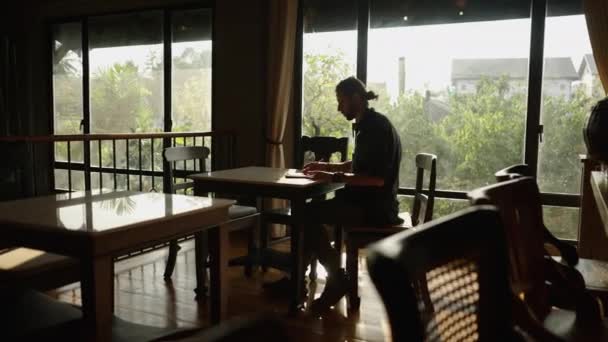 黒いシャツの男が椅子に座っているタブレットに書く オンラインワーカー — ストック動画