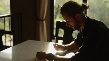 Tabletine sakal çizen yetişkin bir erkek üzerinde güneş ışığı parlayan internet işçisi.