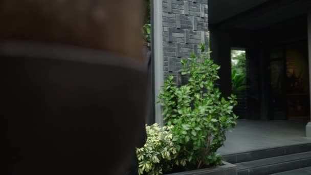 非常に背の高い大人の少年は庭のいくつかの植物の隣に彼のタブレットに触れる オンラインワーカー — ストック動画