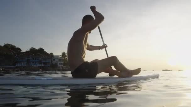 Batılı Bir Adam Arka Planda Bir Kadınla Sörf Tahtasında Kürek — Stok video