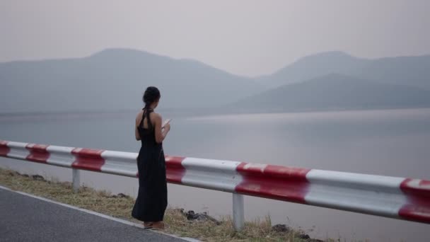 Seorang Gadis Melihat Telepon Genggamnya Depan Sebuah Danau Gunung Yang — Stok Video
