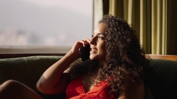 Gülümseyen Latin Kız Cep Telefonuyla Konuşuyor Pencereden Gelen Işıkla Aydınlatılıyor — Stok video