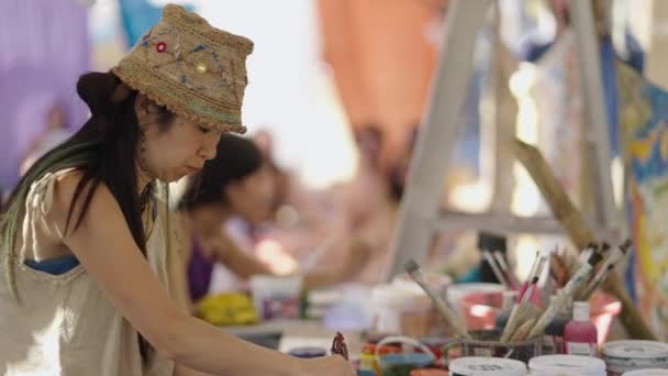 ワークショップのテーブルにペイントを混ぜるアジアの女性 ヒッピーアーティスト — ストック動画