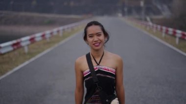 Taylandlı kadın yolda yürüyor ve gülümsüyor.