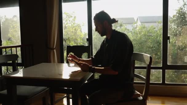 西方男孩看着他的平板电脑 在一个窗口旁边画了个记号 在线工作者 — 图库视频影像