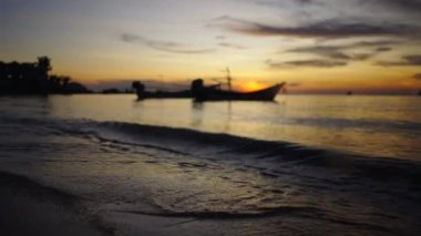 Şok edici bir günbatımının altında Tayland sahillerinde dalgalar kopuyor. 