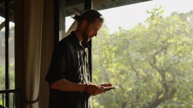 Batılı yetişkin çocuk pencerenin kenarındaki tabletine dokunuyor.