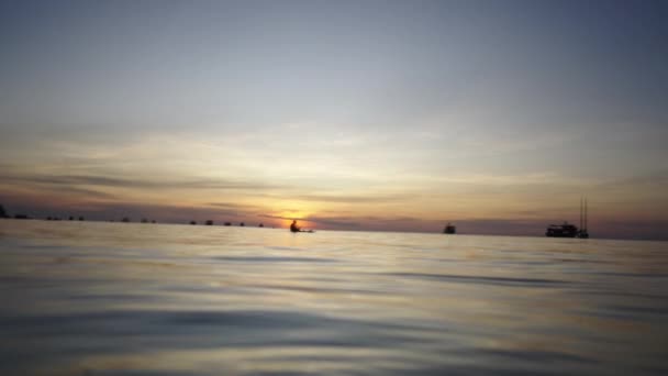 海の日没の背景にパドリングする2人の大人 カップル旅行のコンセプト — ストック動画