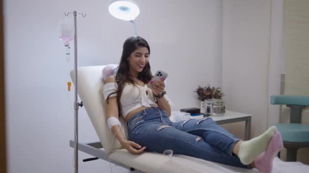 Женщина Сидящая Больничном Столе Развлекающаяся Телефоном Видео — стоковое видео