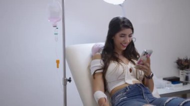 Sedyede yatan ve telefonuna bakarken gülümseyen bir kız. 4K yatay video.