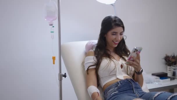 Meisje Liggend Een Brancard Met Glimlacht Terwijl Naar Haar Mobiele — Stockvideo