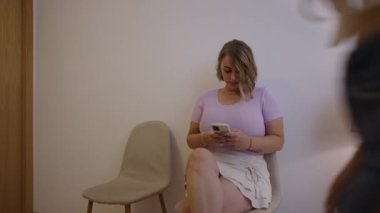 İki kız, klinik bekleme odasında cep telefonlarına bakıyor - sağlık hizmeti konsepti